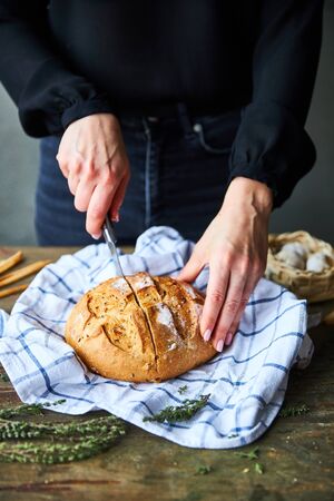 Woman Slicing Bread on tableの写真素材