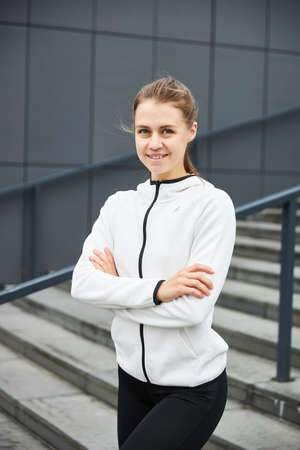 Young smiling female resting after an active fitness training while standing against gray wall with copy space area for your text message, satisfied fit woman resting after an active fitness trainingの写真素材