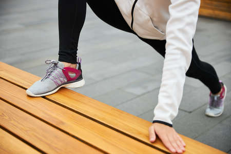 A young girl in a tracksuit warms up before jogging in the urban environment.の写真素材