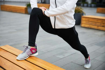 A young girl in a tracksuit warms up before jogging in the urban environment.の写真素材