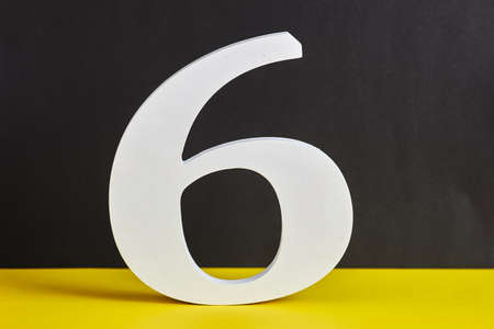 Number six made from wood on black and yellow background