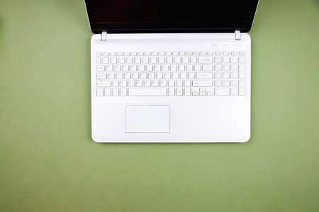 Open white laptop on an isolated green background. Top view.