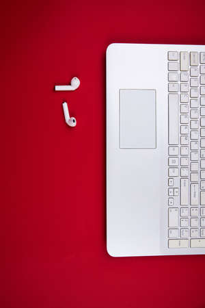 View from above on a open white laptop, wireless headphones. Isolated red background. Top view.の写真素材