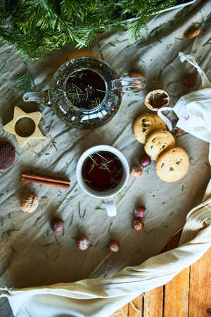 Gingerbread cookies, fruit tea and fir tree branches on a wooden black background. Christmas and New Year treat.の写真素材