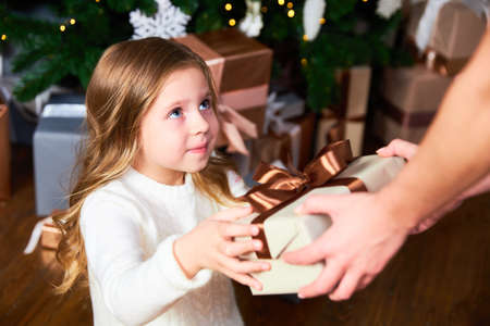 Girl looks at mom, mom gives girl a gift for Christmasの写真素材