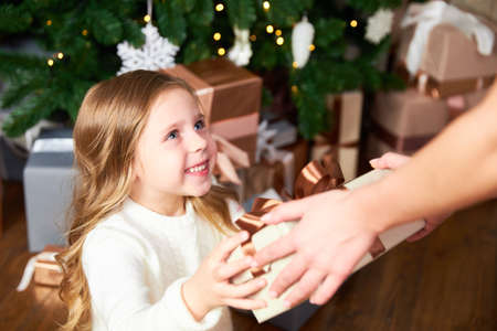 Girl receives gift from mom for Christmas, girl happy and looks at momの写真素材