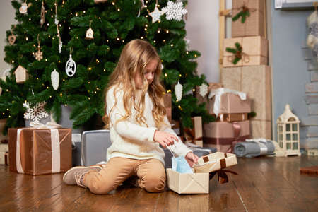 A girl pulls out a medical mask from a Christmas present.の写真素材