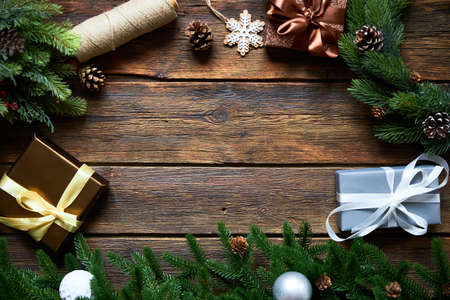 Preparing for Christmas or New Year holiday. Flat-lay of fur tree branches, evergreen wreaths, christmas wraped gift, wooden table background, top view, copy spaceの写真素材