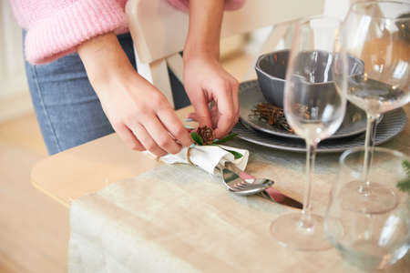 The woman serves a festive Christmas table in the white kitchen for the family holiday, only hands,...