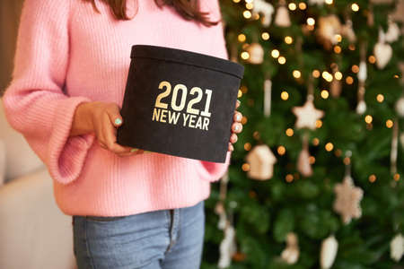 A woman holds a black gift with the inscription 2021 in her handsの写真素材