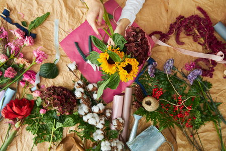 Flat lay composition florist creates a bouquet on craft paper and pink background paperの写真素材