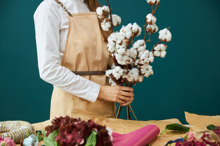 A woman florist in working clothes creates a bouquetの写真素材