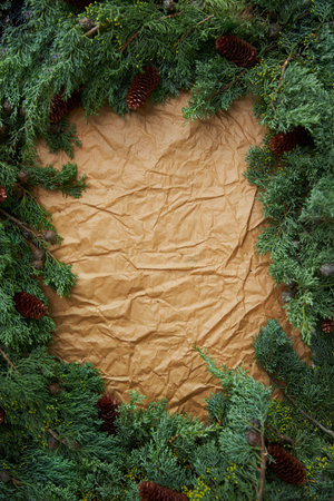 Empty place on crafting brown parchment paper. Surrounded by green branches spruce and cones.の写真素材