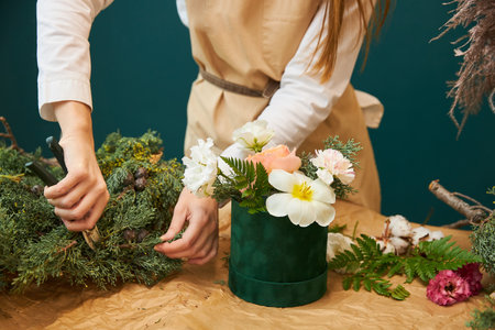 A female florist creates a bouquet for Christmas from flowers and branches of spruce. The work of a florist.の写真素材
