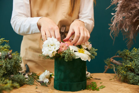A female florist creates a bouquet for Christmas from flowers and branches of spruce. The work of a florist.の写真素材