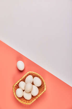 Eggs for Easter in a basket pink white backgroundの写真素材