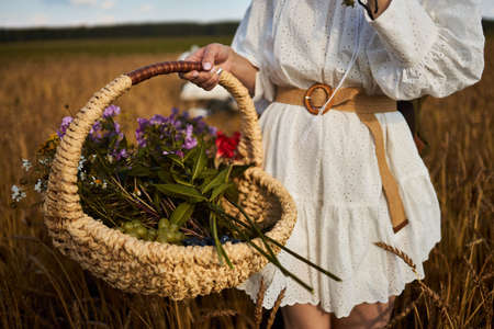 A woman holds a basket with summer wildflowersの写真素材