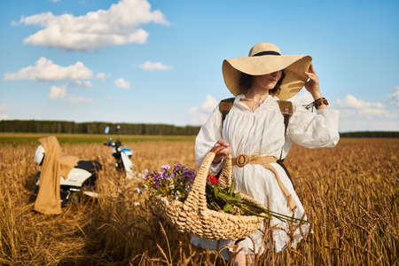 A woman holds a basket with summer wildflowersの写真素材