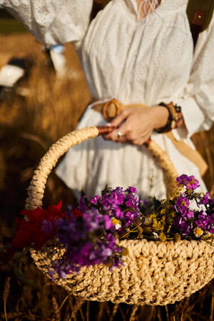 A woman holds a basket with summer wildflowersの写真素材