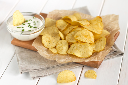 Potato chips on a parchment on a table. Concept of unhealthy food.の写真素材