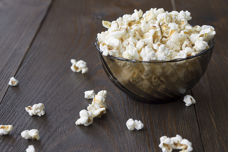 Salty popcorn on the wooden table. Bowl of popcorn with cheese flavor.の写真素材
