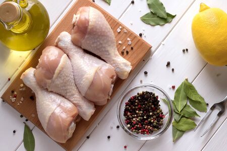 Fresh raw chicken meat on cutting board with spices, oil and lemon. Top view.の写真素材