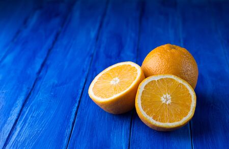 Juicy whole orange and two halves on the dark blue wooden background. Selective focus.の写真素材