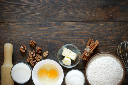 Ingredients for baking cake with walnuts on a dark wooden table. Top view, copy space.の写真素材