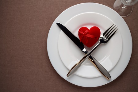 Valentines day table setting with red heart and cutlery on a plate. Concept of romantic dinner. Top view, copy space.の写真素材