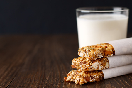 Homemade no bake granola bars with glass of milk on rustic wooden table. Healthy snacks for diet. Copy space.の写真素材
