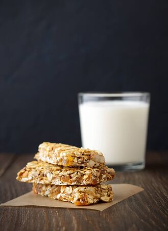 Three granola bars on parchment with milk on rustic wooden background. Healthy snacks on paper, copy space.の写真素材