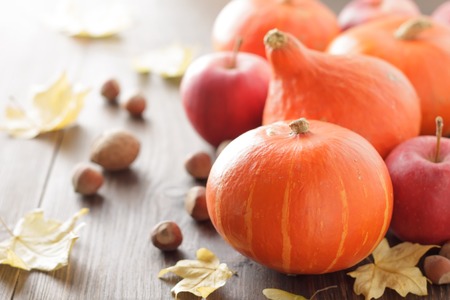 Fall background with pumpkin hokkaido, apple, nuts and leaves on wooden table. Hello autumn concept with copy space.の写真素材