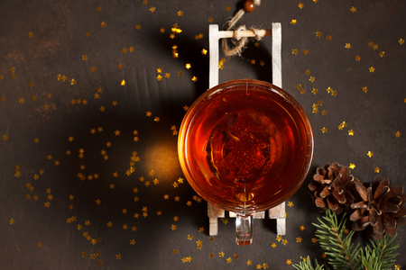 Glass cup of tea on wooden sled with fir branches on brown stone background with golden stars. Top view with copy space.の写真素材