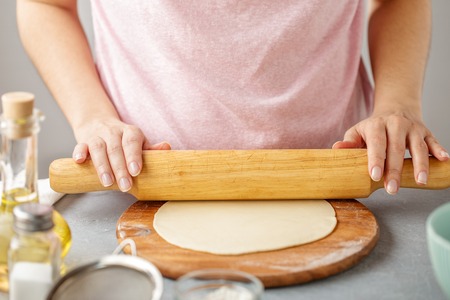 Woman roll out the dough on the wooden cutting board. Step by step recipe of homemade tortillas.の写真素材