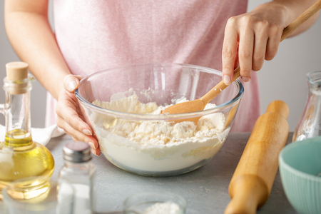 Woman mix flour, baking powder, salt, oil and hot water in the glass bowl. Step by step recipe of homemade tortillas.の写真素材