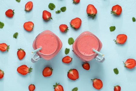 Two mason jars with strawberry on blue background top view.の写真素材