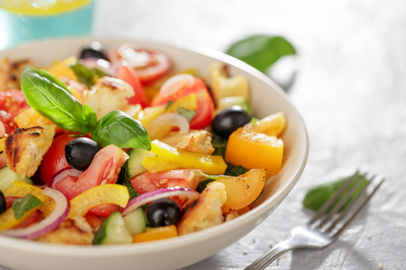 Panzanella salad with heirloom tomatoes and ciabatta in ceramic bowl on the kitchen table close-up.の写真素材