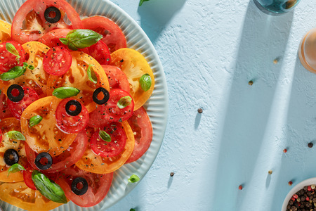 Mediterranean tomato salad in the plate on blue pastel background. Top view with copy space.の写真素材