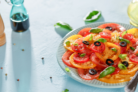 Homemade vegetarian tomato carpaccio salad in blue plate on blue background with copy space.の写真素材