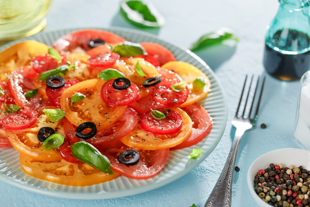 Freshness summer tomato salad carpaccio on blue plate on the table with fork and balsamic sauce.の写真素材