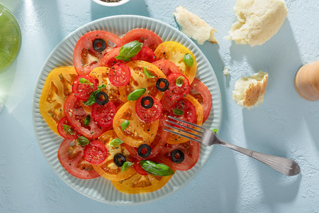 Healthy summer tomato salad and pieces of bread on blue table ready to eat top view.の写真素材