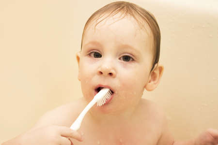 cute little boy cleans his teeth in a bath ,and plays with a toothbrush