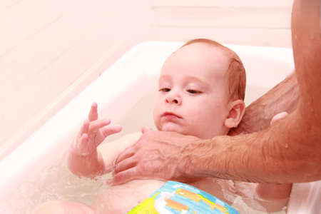Father teaching baby to swim. Portrait of a charming 7 months child in the classroom in a swimming...