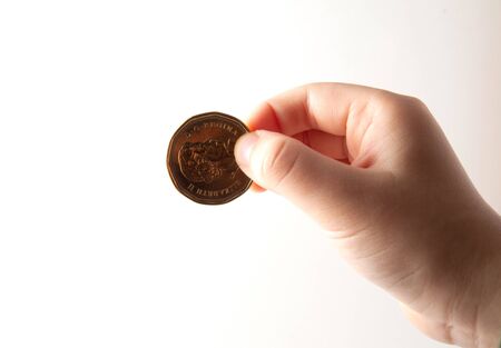 Child hand holding a coin on white backgroundの写真素材