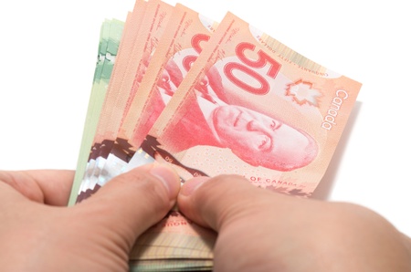 Hand holding a series of Canadian banknotes on white backgroundの写真素材