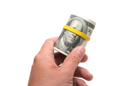 Roll of us bank notes with 100 dollars at the surface, yellow rubber band over the eyes