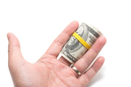 Roll of us bank notes with 100 dollars at the surface, yellow rubber band over the eyesの写真素材