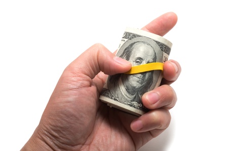 Roll of us bank notes with 100 dollars at the surface, yellow rubber band over the eyesの写真素材