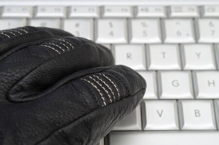 Hacking concept with hand in black leather glove over the laptop keyboardの写真素材
