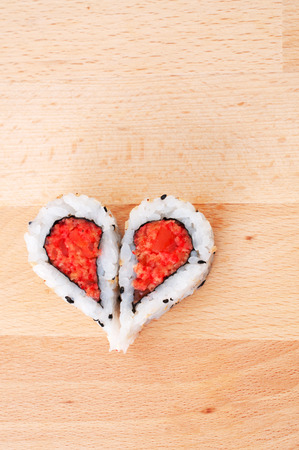 Two pieces of sushi forming the heart shape on wooden cutting boardの写真素材
